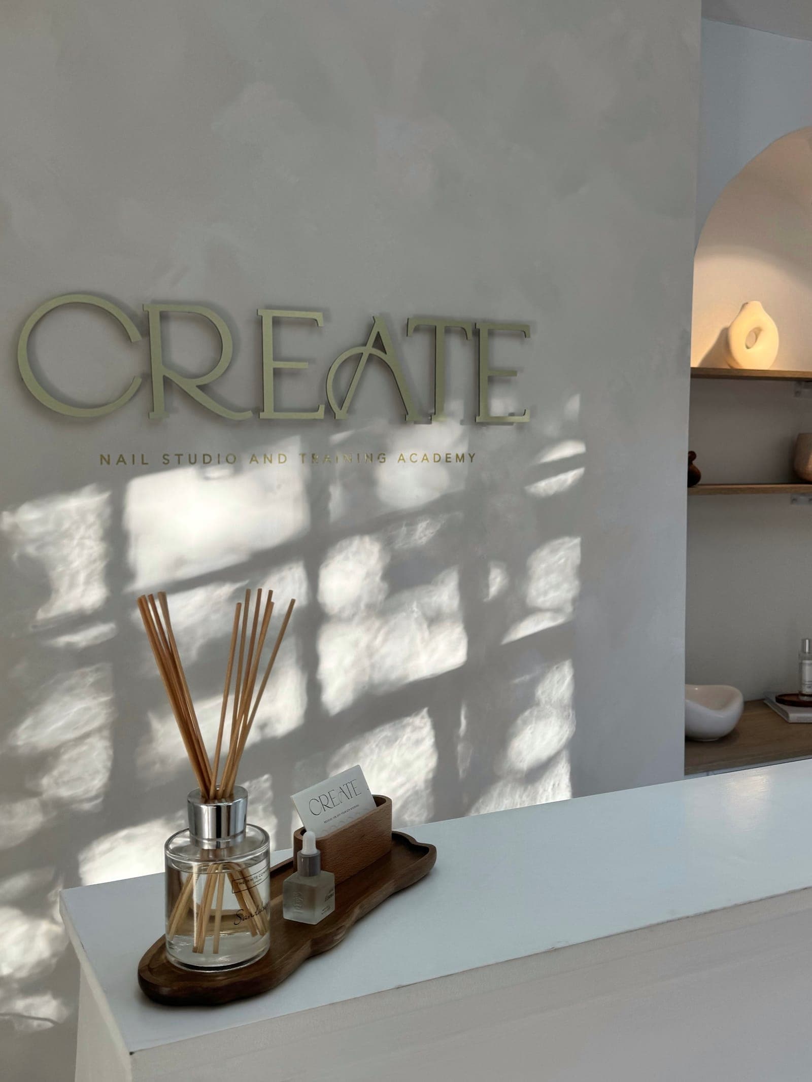 The CREATE studio — gold CREATE lettering on a warm plaster wall in dappled sunlight